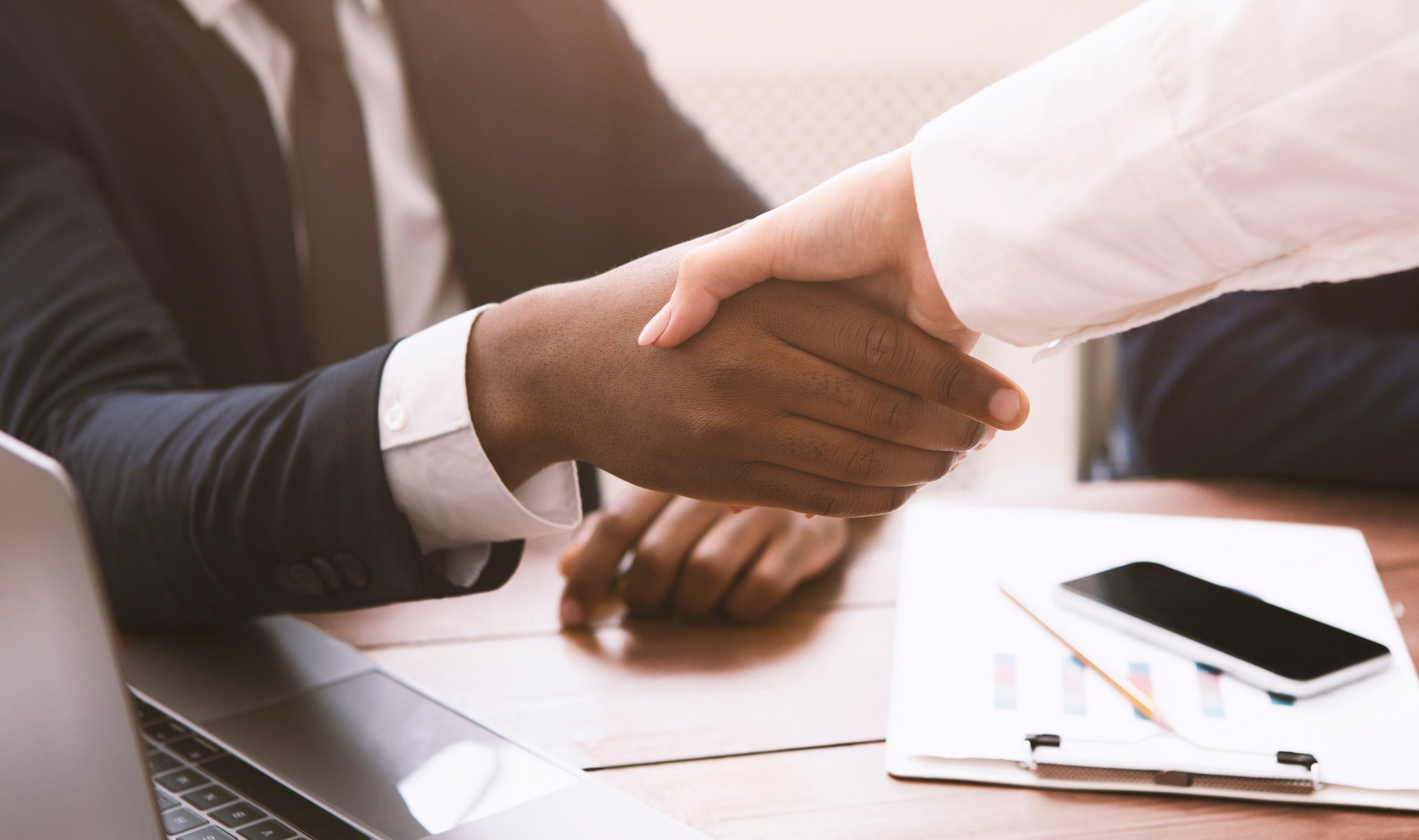 Black and white business partners handshaking on meeting